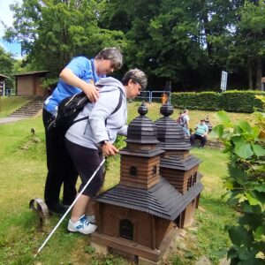 Turisti pri miniatúrach drevených kostolíkov v Uliči