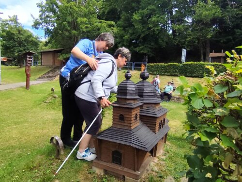 Turisti pri miniatúrach drevených kostolíkov v Uliči