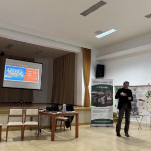 pán prezentuje v pozadí je plátno a baner